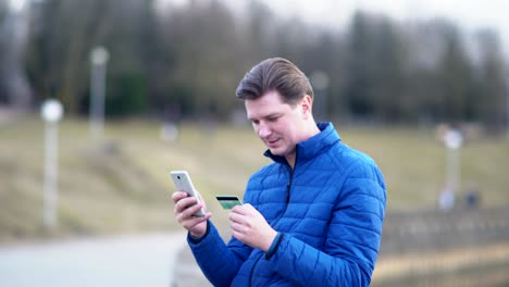 man makes purchases with a credit card and phone