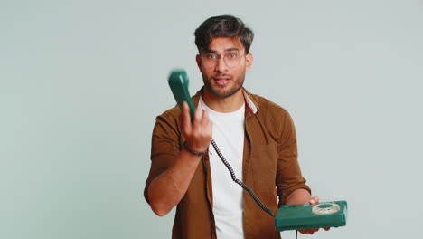 Indian-man-talking-on-wired-landline-vintage-telephone,-advertising-proposition-of-conversation