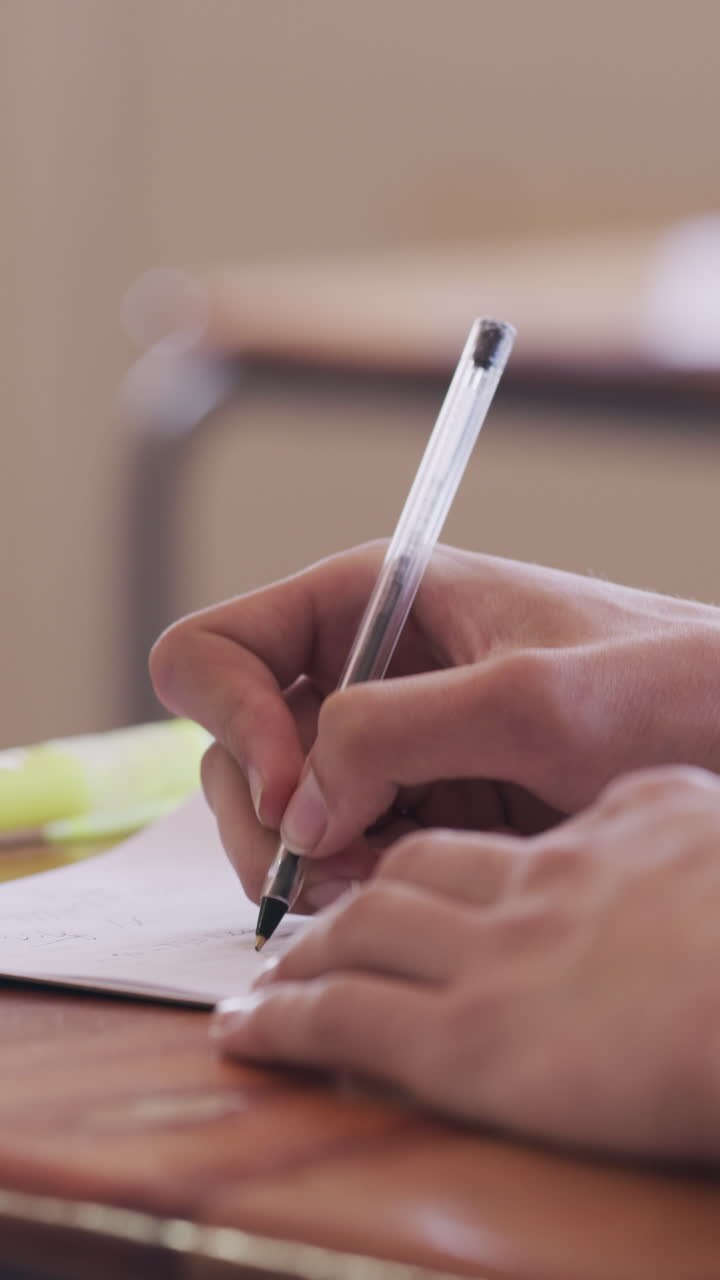 Primo piano di mani che scrivono su carta con una penna