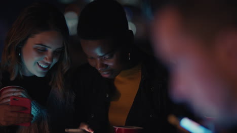 group-of-friends-relaxing-on-rooftop-at-night-using-smartphone-technology-texting-sharing-social-media-lifestyle-browsing-online-enjoying-weekend-party