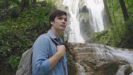 young man with waterfall deep in the jungle, slow motion