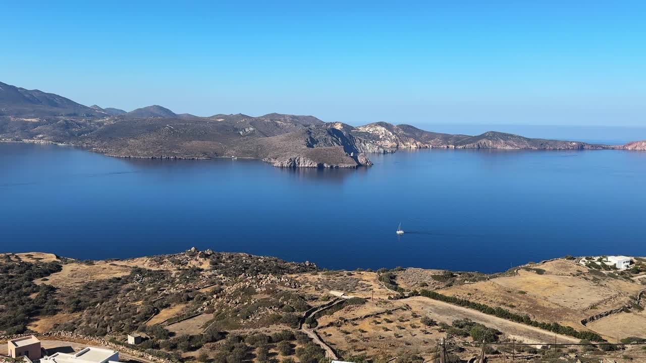 An island view showcases the deep blue ocean with a boat gently drifting by