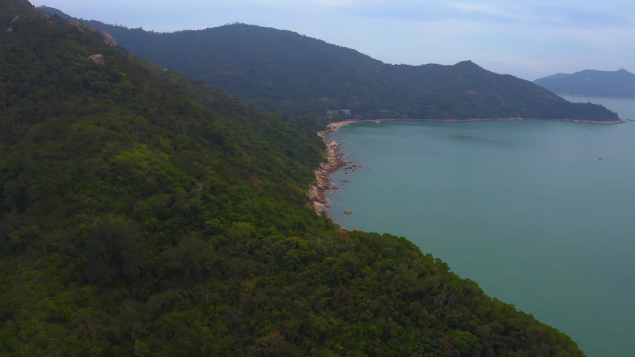 toma de drones de una costa montañosa llena de vegetación y acantilados durante el día
