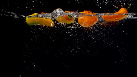 vibrant sweet peppers being dropped into water in slow motion