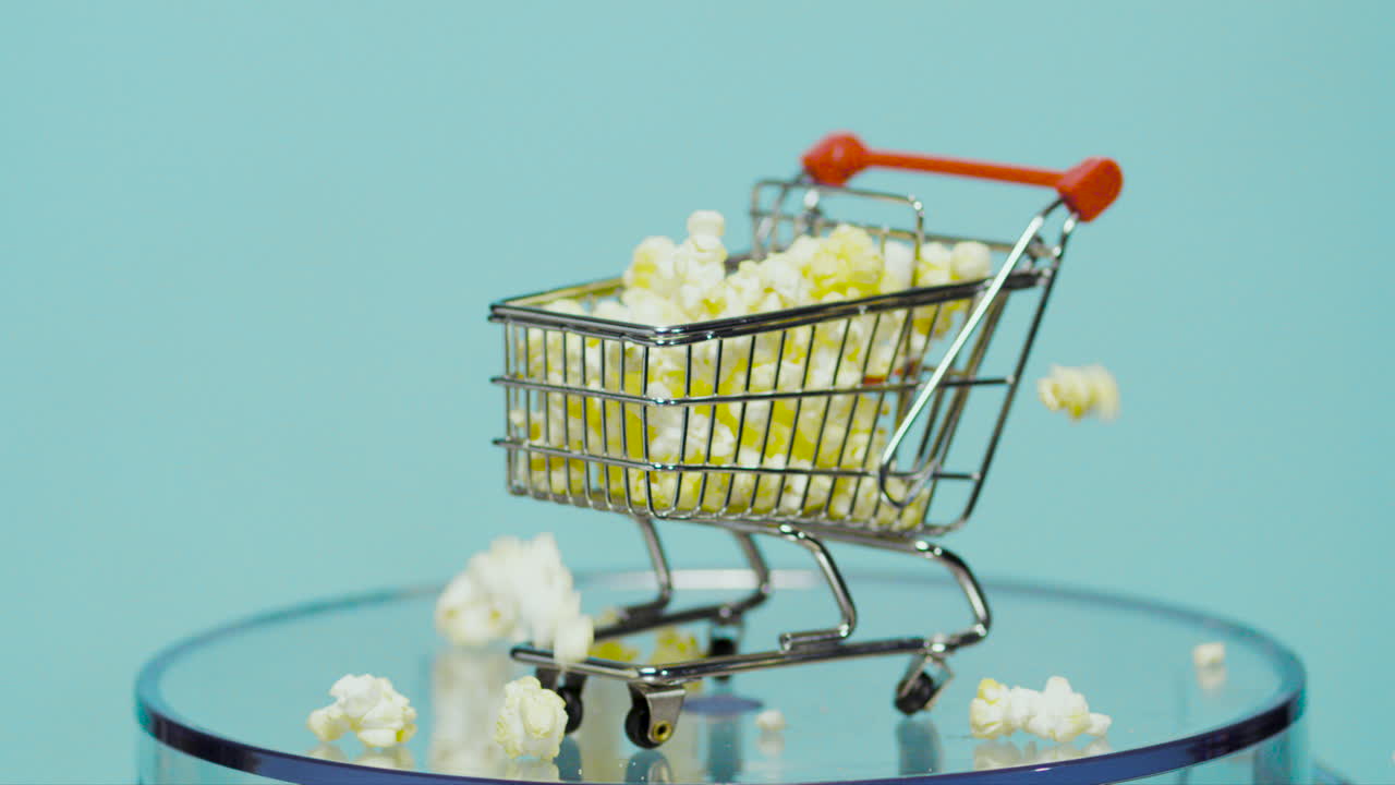 kart de compras lleno de palomitas de maíz en cámara lenta con fondo azul bebé