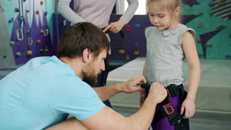 parent helping child put on rock climbing harness
