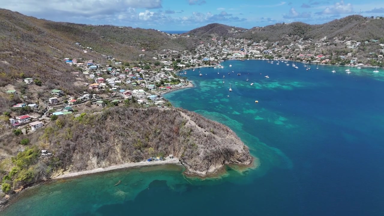 Vista aerea del porto naturale di un blu profondo, della penisola costiera e dei villaggi circostanti dell'isola di Bequia, Saint Vincent e Grenadine.