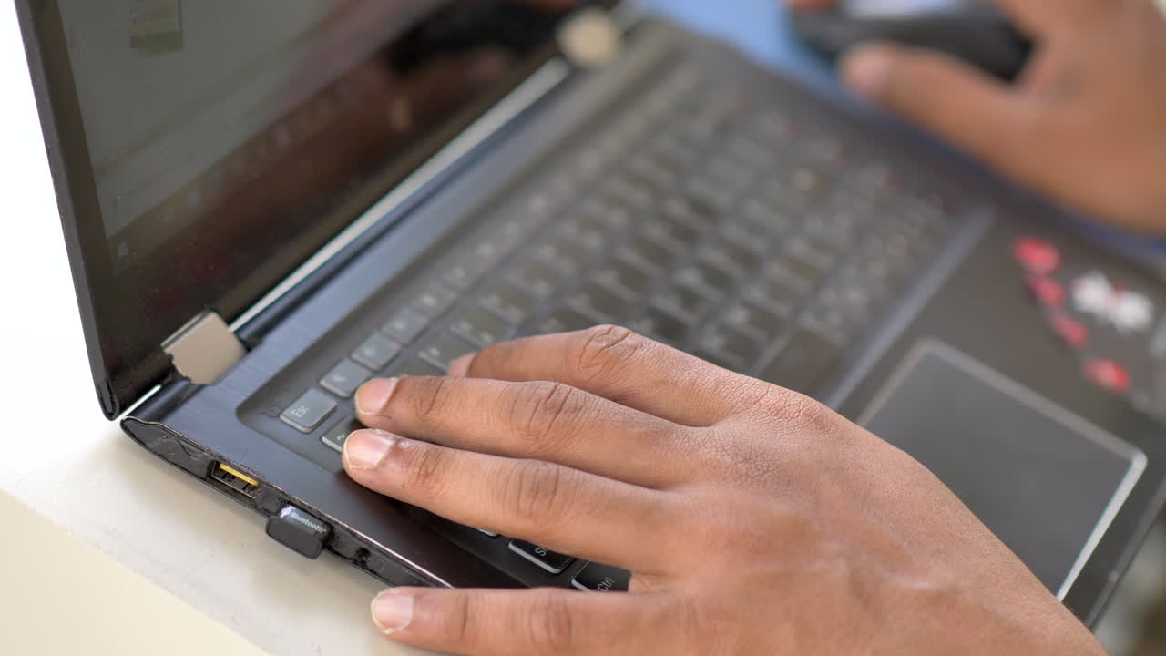 Top down view of someone quickly writing on laptop. Narrow depth of field. Reflection of hand visible in screen