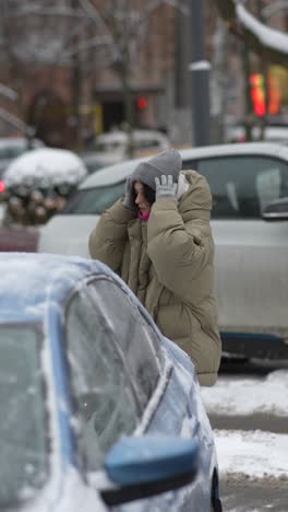 woman in winter clothes standing near a snow-covered car