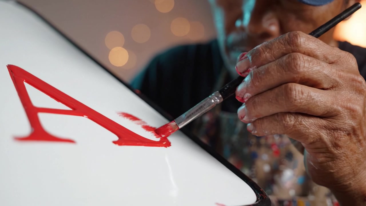 Artigiano che dipinge una vistosa lettera A rossa su un'insegna, mostrando precisione e creatività nell'artigianato con un focus sui dettagli e un'esecuzione abile