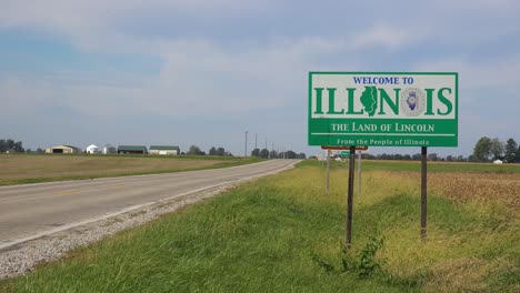 el cartel a lo largo de un camino rural abandonado a través del campo indica la línea estatal de illinois