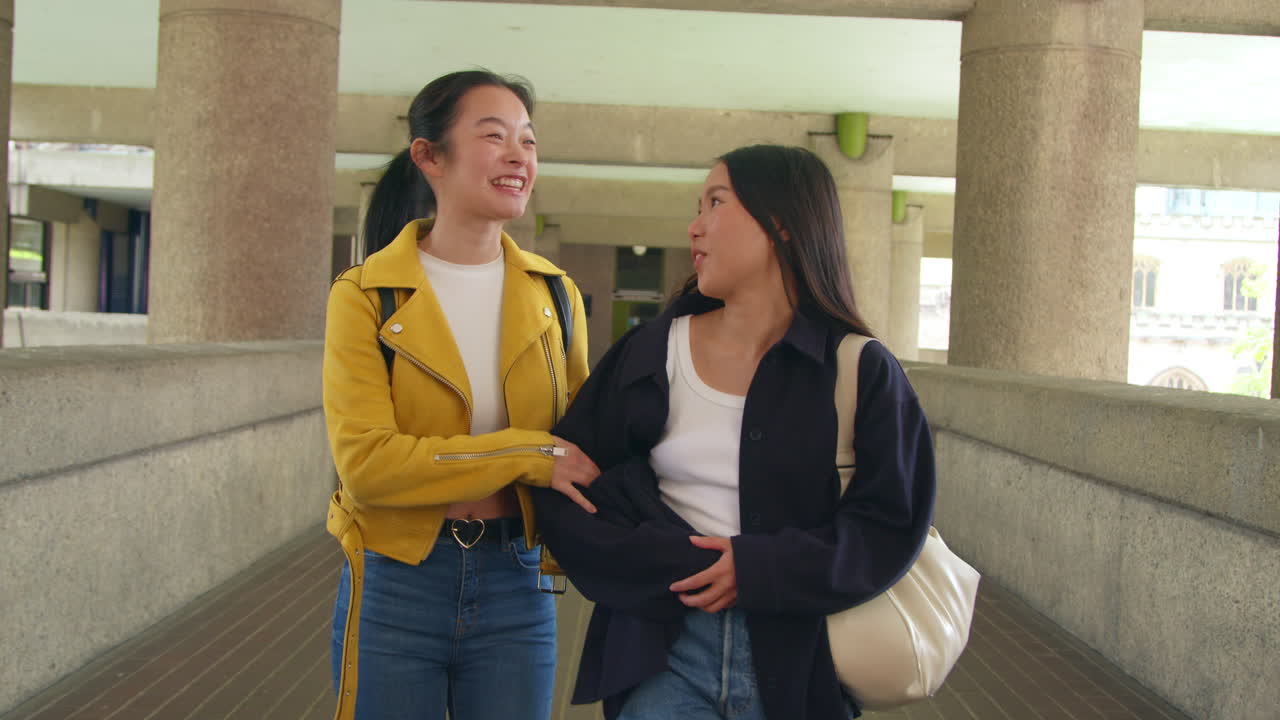 vista frontal de dos jóvenes amigas caminando juntos por el centro barbican en la ciudad de londres 1