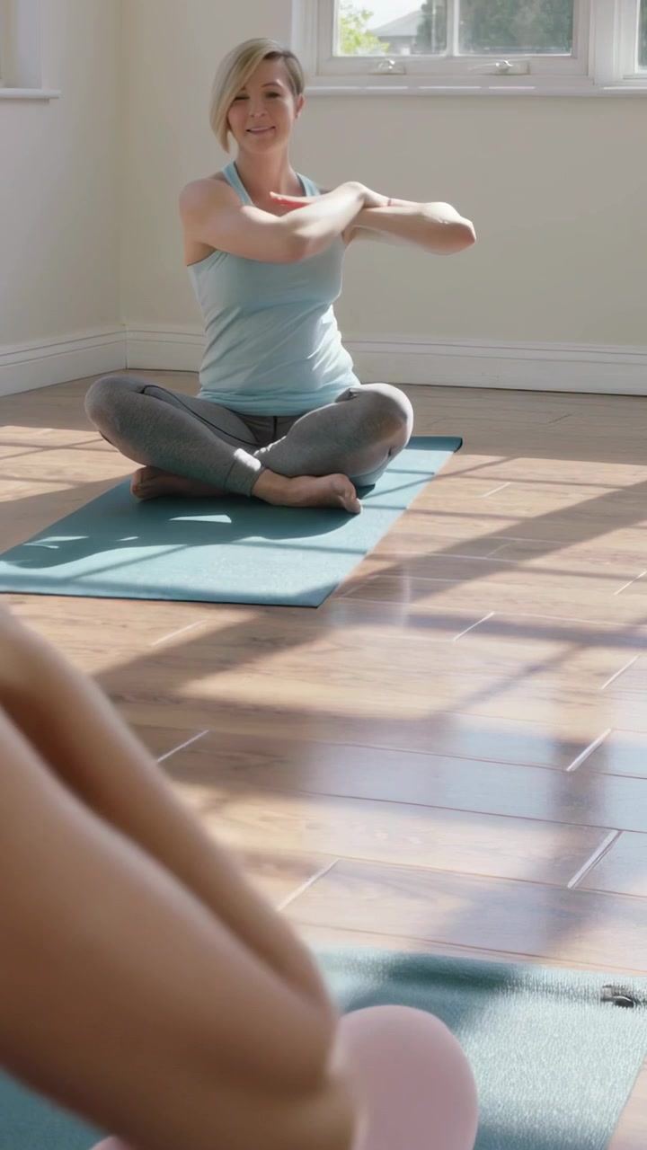 Video verticale: Allenatore che annuisce e dà indicazioni, incrociando le braccia su un tappetino blu in studio, in canotta e leggings.