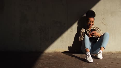 Mixed-race-woman-laughing-on-smartphone-under-bridge