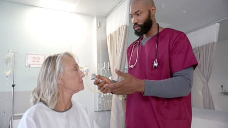 african american male doctor with otoscope examining ear of caucasian female patient at hospital