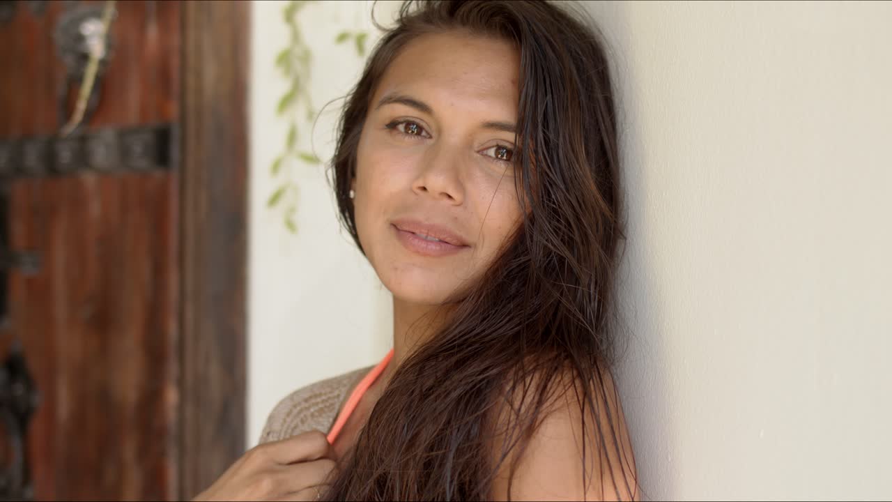 sensual morena apoyándose en la pared blanca en la terraza