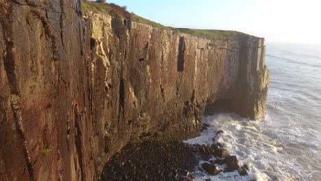 Sunrise-at-ocean-and-wave-splashing-in-the-rocks,-aerial-footage,-Torres,-Brazil