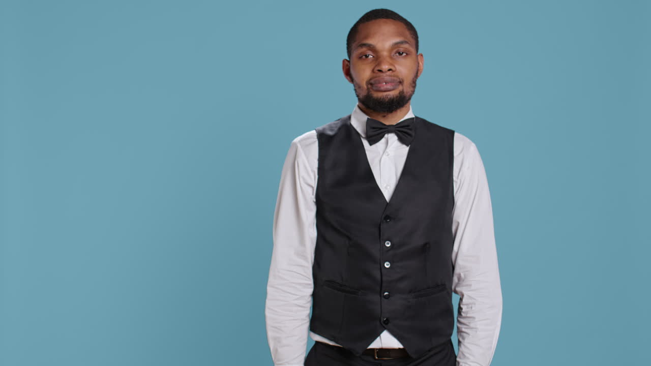 Classy hotel bellboy in tuxedo giving the room access key card to guest