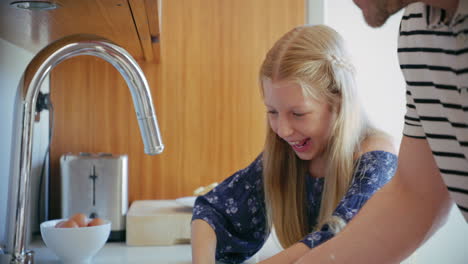 daughter and father washing dishes and having fun in the kitchen