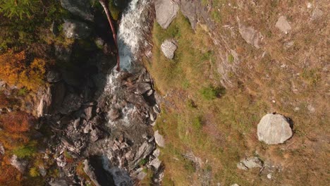 Top-View-Of-Cascading-Stream-On-Rugged-Mountains-During-Sunny-Day