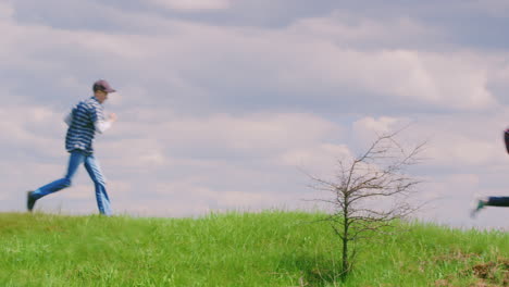 two young teenage boys run along the green hill 1