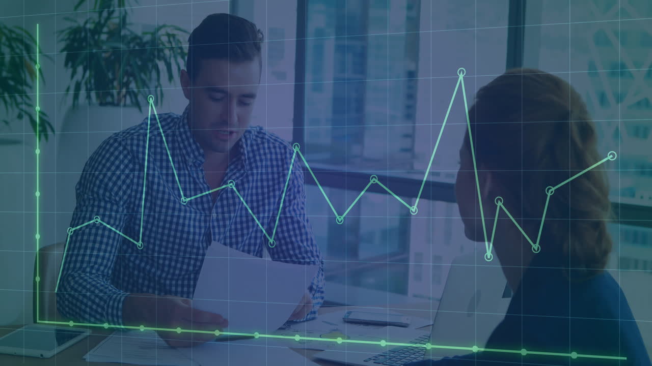 Man reviewing documents while woman listening at office meeting with financial graph overlay