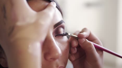 primer plano del proceso maquilladora femenina aplicando suavemente un delineador negro usando un pincel particular