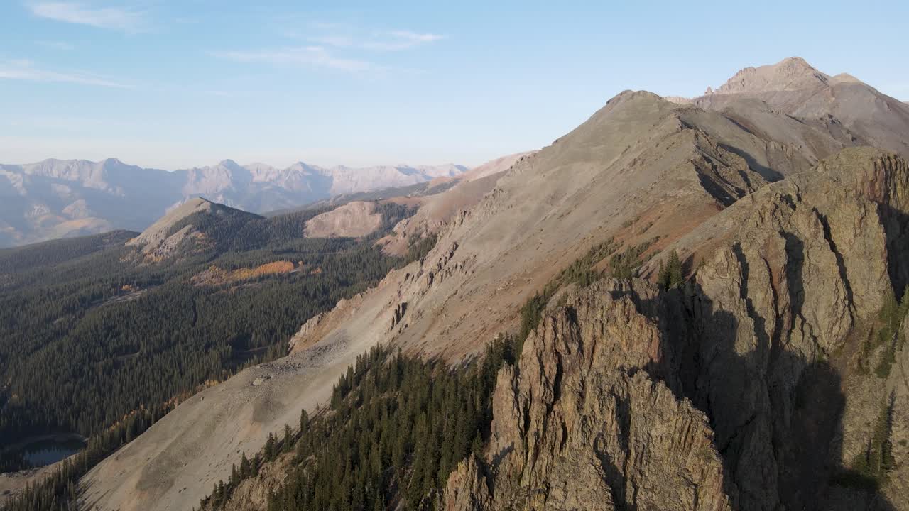 Pengambilan gambar drone terbang tinggi, berputar perlahan, dari puncak Pegunungan Rocky dekat Telluride, Colorado, pada hari yang cerah di musim gugur