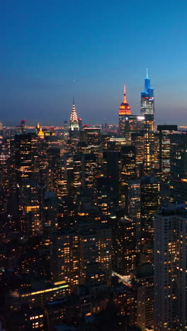 Amazing New York city full of lights in the evening. Beautiful shining skyscrapers at the backdrop of blue evening sky. Vertical video