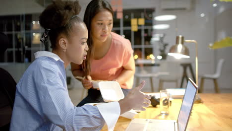 young african american woman and biracial woman collaborate in a business office