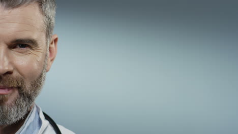 close up of the half face of the cheerful man doctor with a beard smiling and looking straight to the camera