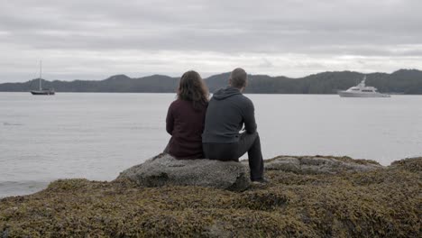 couple watching salmon on rocky beach cloudy