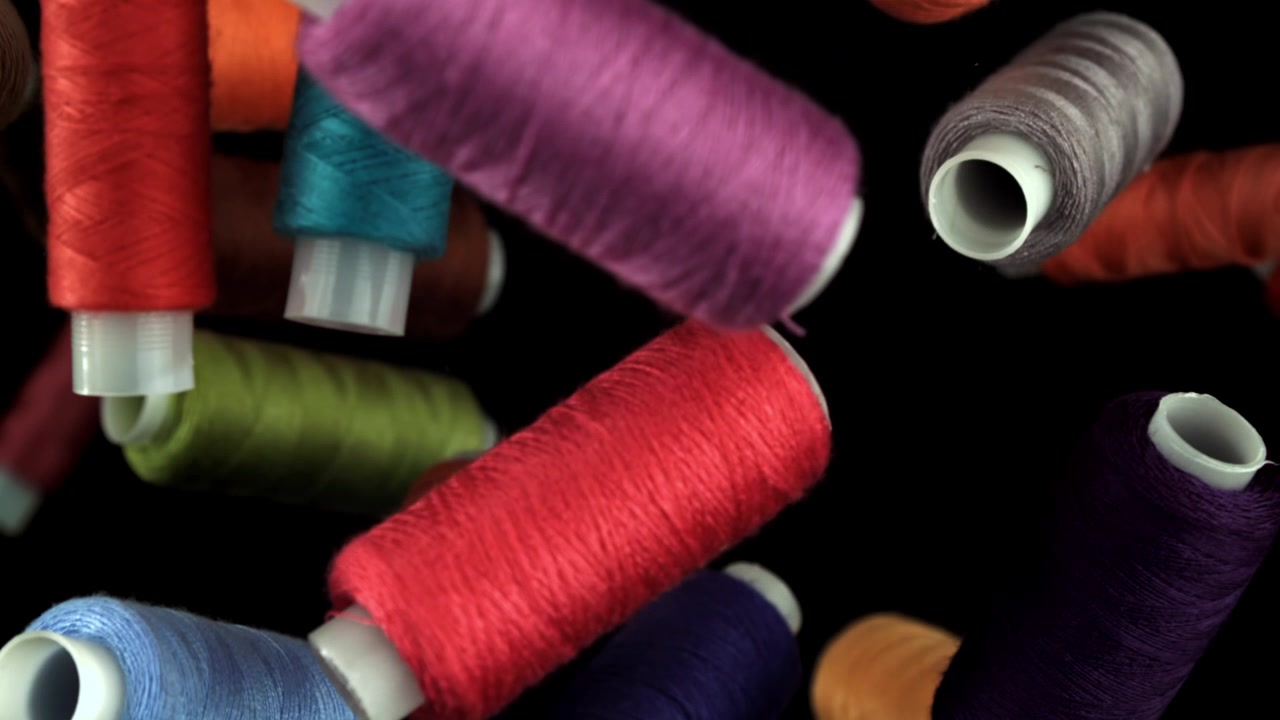 Colorful Spools of Thread Falling in Slow Motion on Black Background
