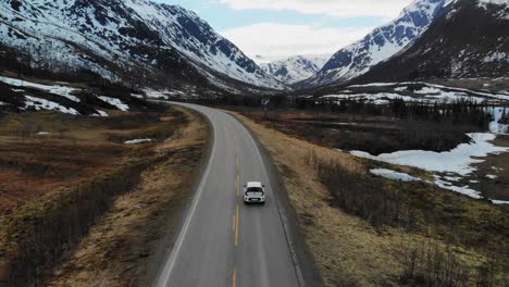 Drohne,-Die-Einem-Auto-In-Einer-Wunderschönen-Landschaft-Mit-Wäldern-Und-Bergen-Folgt