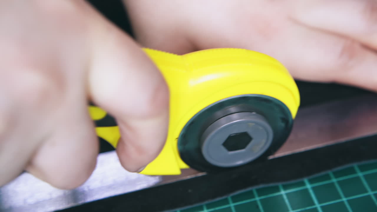 el sastre corta tejido de cuero negro con un cortador rotativo amarillo