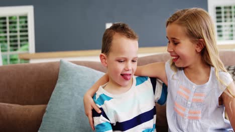 Smiling-boy-and-girl-sitting-on-sofa-