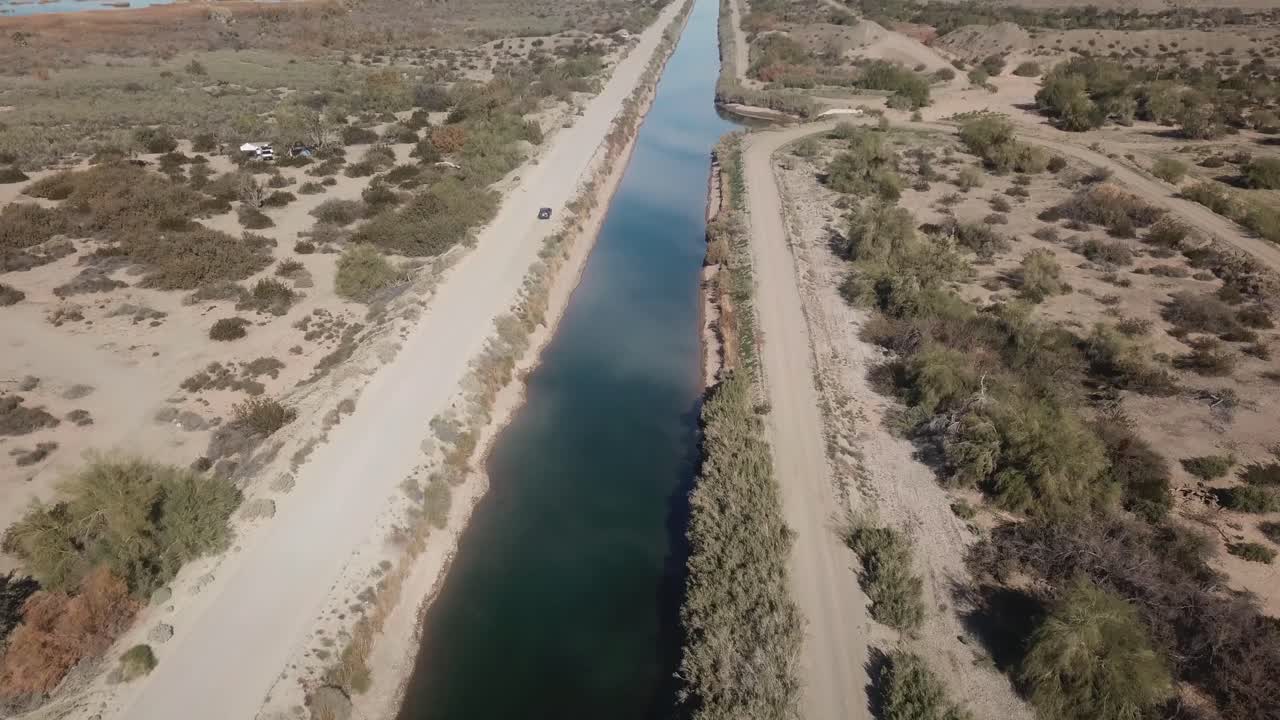 Vista aerea con drone di un veicolo che percorre il Canale a Gravità del Gila - Distretto di Irrigazione di Yuma nell'Arizona meridionale