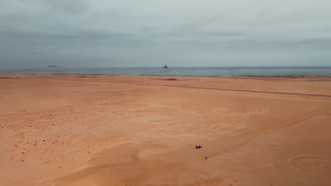 desert coastline with oil rig and people