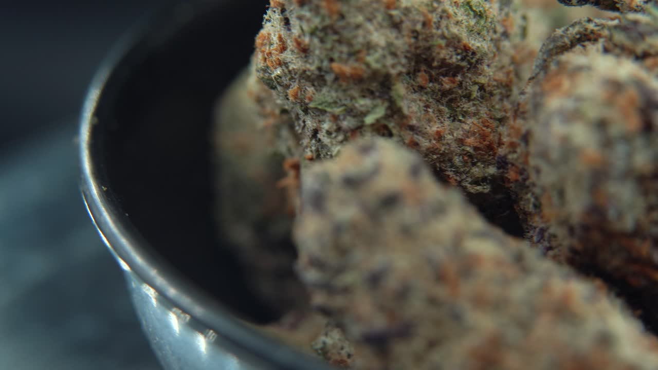 Macro of a premium cannabis bud rotating on a 360-degree display stand, showcasing its purple trichomes, vibrant hues, and sharp texture. Ideal for showcasing top-tier cannabis product 4k