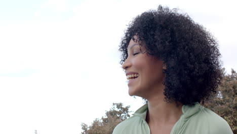 biracial woman smiling outdoors with trees and clear sky, copy space
