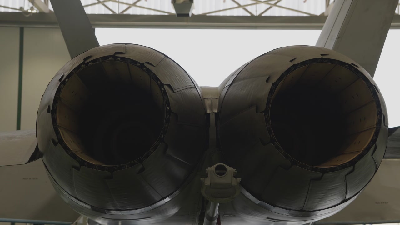 Twin engine military jet rear view in maintenance hangar