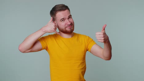 Bearded-man-in-t-shirt-looking-at-camera-doing-phone-gesture-like-says-hey-you-call-me-back