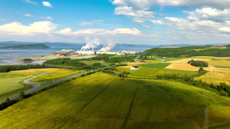 Fiborgtangen-industrial-site-on-Trondheimsfjord,-drone-hyperlapse-over-farm-land