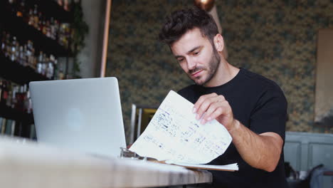 Männlicher-Besitzer-Einer-Restaurantbar-Sitzt-Mit-Laptop-An-Der-Theke-Und-Arbeitet