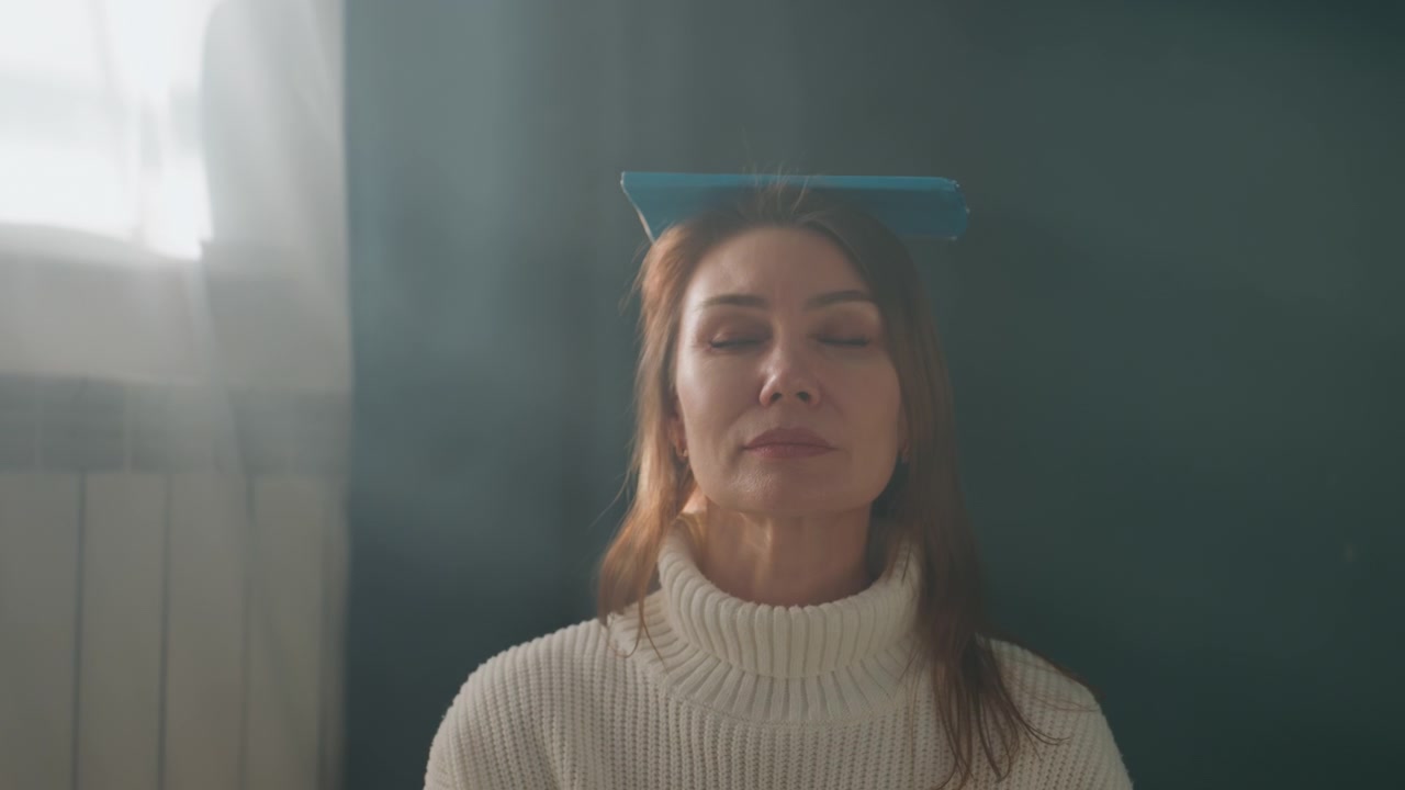 Older caucasian woman balancing book on head in sunlit living room, knitted sweater, eyes closed, practicing posture and breathing for grammar and diction coaching, calm mindful routine, soft window