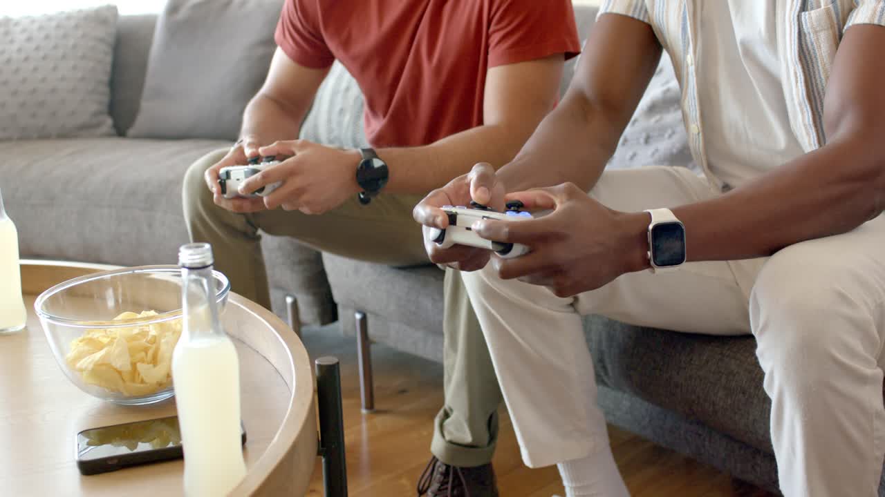 With game starting, two friends are reaching for game controllers on coffee table to begin match