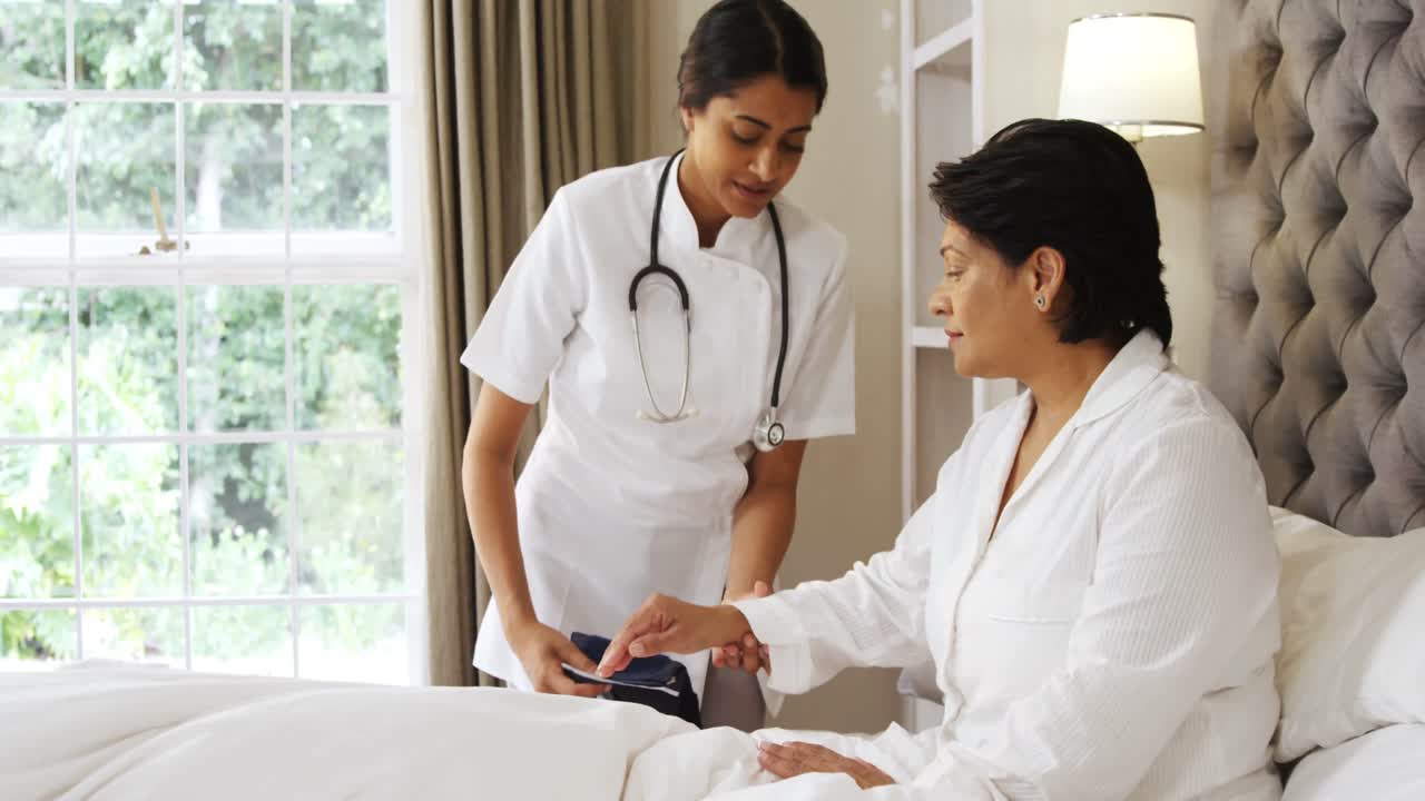 Female doctor measuring blood pressure of mature woman in bedroom 4k