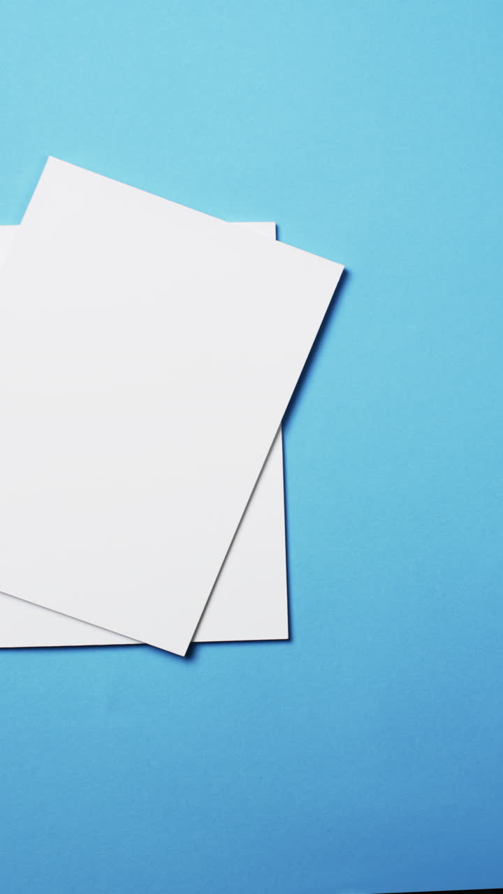 Vertical video of books with white blank pages and copy space on blue background