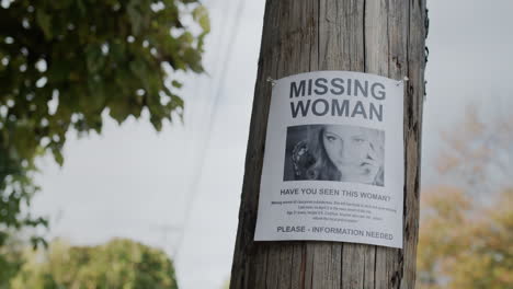 an advertisement for the missing woman hangs on a wooden pole. search for missing people