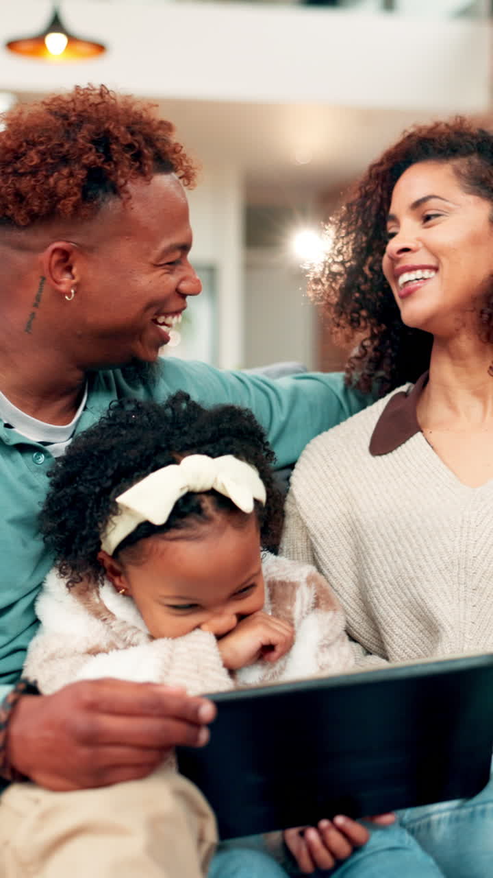 Famiglia afroamericana felice che ride mentre guarda un tablet a casa
